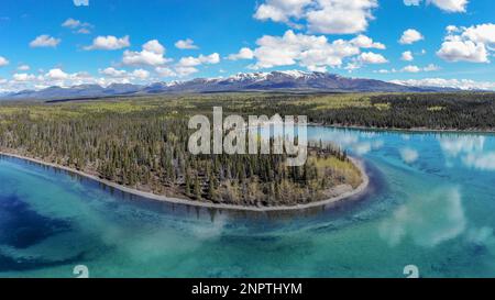 Stunning wilderness lake views in northern Canada during summer time. Snow capped mountains and incredible nature landscape. Stock Photo