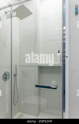 Close up modern glass shower in the white ceramic bath room. Interior of a luxury hotel bathroom with glass shower cabin. Transparent shower cabin. Stock Photo