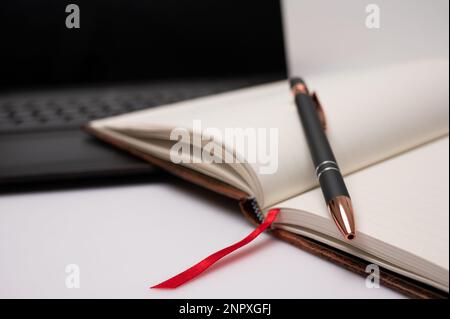 An opened notebook with a laptop and pen on a desktop with a feel for a home office or creative writing. Stock Photo