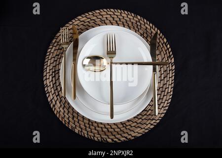 Plates and utensils, Plate, Bowl and golden cutlery against dining table background, side view. Modern craft ceramic tableware. Stock Photo