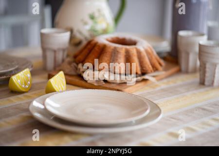 Easter lemon bundt cake, Babka sprinkled with powdered sugar on a festive table decorated with ceramic dishes. Rustic, Scandinavian style in table set Stock Photo