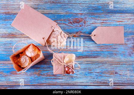 View of souvenirs with seashells in gift bags with space for greeting text. Still life on a wooden background Stock Photo