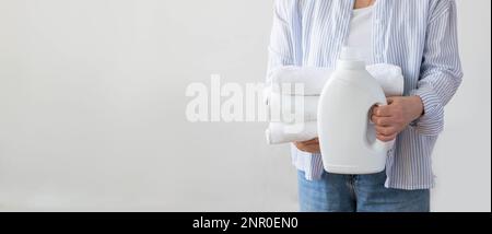 Woman holds stack of white towels bottle of detergent in her hands, of cleaning washing cleanliness Stock Photo