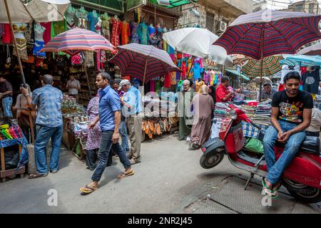 A busy section of the Khan el-Khalili Bazaar shaded by umbrellas at Cairo in Egypt. The stores are selling souvenirs, bags and textiles. Stock Photo