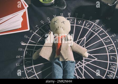 Voodoo doll pierced with needle on table. Curse ceremony Stock Photo