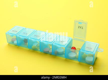 Plastic box with different pills on yellow background Stock Photo