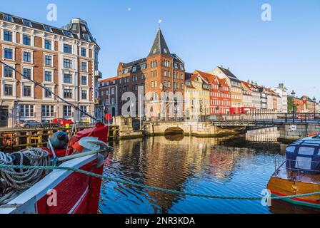 Moored boats and canal bridge with view of Bethel aka Somandshjem hotel and colourful 17th century apartment buildings along Nyhavn canal, Copenhagen. Stock Photo