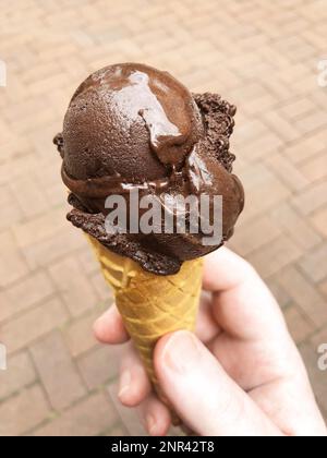 hand holding dark chocolate ice cream cone, authentic mobile image from personal perspective Stock Photo