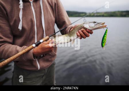 close up man holding freshly caught fish with lure Stock Photo