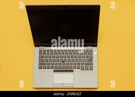 Modern open business laptop technology with blank black screen isolated on yellow background Stock Photo