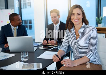 My job is truly fulfilling. Portrait of a young businesswoman working in the boardroom with her colleagues in the background. Stock Photo