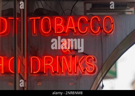 A red neon outside a shop saying in 'Tobacco & Drinks'. Stock Photo