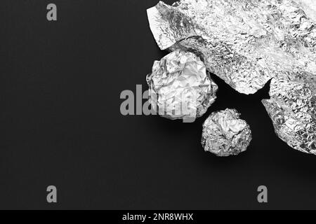 Crumpled balls of aluminium foil on dark background Stock Photo