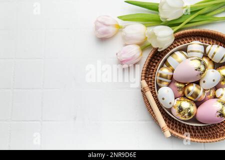 Easter golden eggs and pink tulips on white tile  background. Top view. Happy Easter composition. Greeting card. Stock Photo