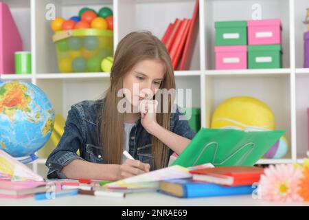 girl siting at table with globe and studying Stock Photo