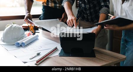 People adviser construction site engineers. working drawing on blueprint and discussing the floor plans over blueprint architectural plans at on Stock Photo