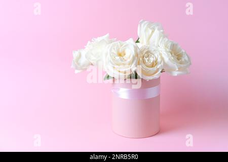 Bouquet white roses on pink background in a box. Mother's Day, Valentine's Day, birthday celebration concept. Greeting card. Copy space for text. Stock Photo