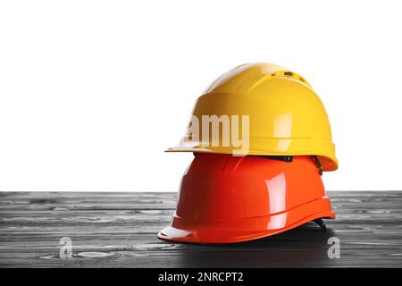 Different hard hats on wooden table against white background. Space for text Stock Photo