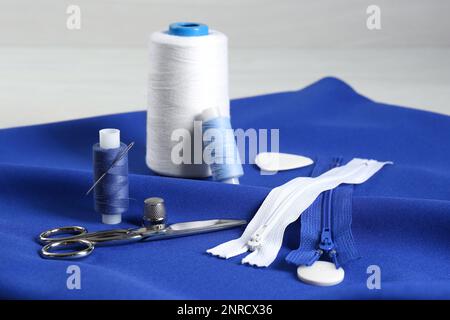 Composition with different sewing supplies on blue fabric Stock Photo