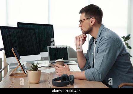 Programmer with coffee working at desk in office Stock Photo