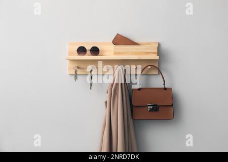Wooden hanger for keys with different stuff on light grey wall Stock Photo