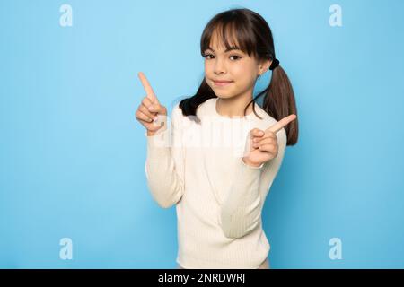 Portrait of adorable kind sweet little child girl impressed face expression promote offer isolated on blue color background Stock Photo