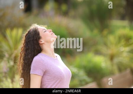 Woman breathing fresh air standing in a green park Stock Photo