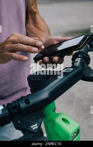 Close-up of hands using smart phon to unlock electric push scooter Stock Photo