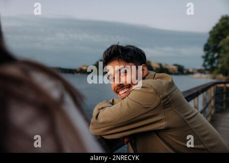 Portrait of happy young man leaning on railing at dusk Stock Photo