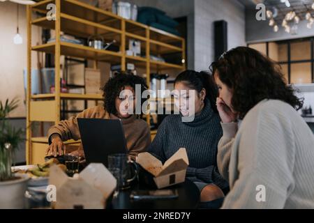 Multiracial female programmers discussing over laptop while working in startup company Stock Photo