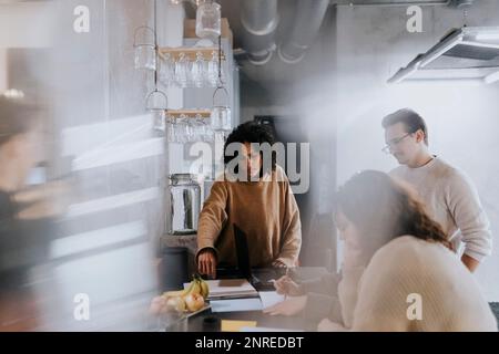 Multiracial male and female colleagues discussing during meeting in ...