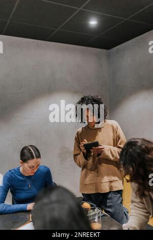 Businesswoman taking notes while discussing with female colleagues in creative office Stock Photo