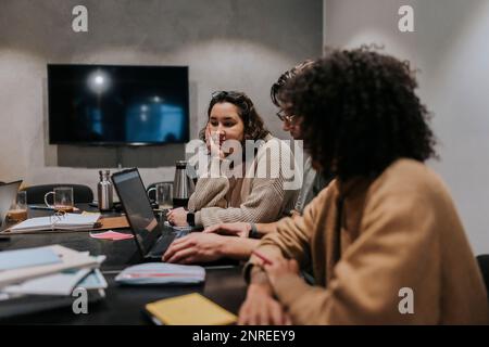 Multiracial computer programmers discussing over laptop in board room at office Stock Photo