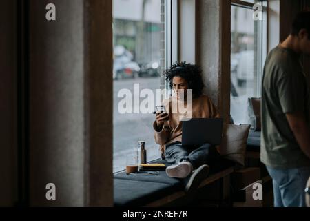 Businesswoman using smart phone while working by male colleague in startup company Stock Photo