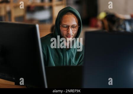 Male computer programmer working on laptop in creative office Stock Photo