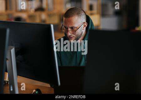 Young male programmer working on computer in startup company Stock Photo