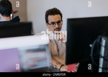 Dedicated businessman working on computer at creative workplace Stock Photo