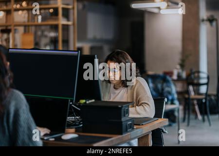 Young female programmers working on computers at desk in startup company Stock Photo