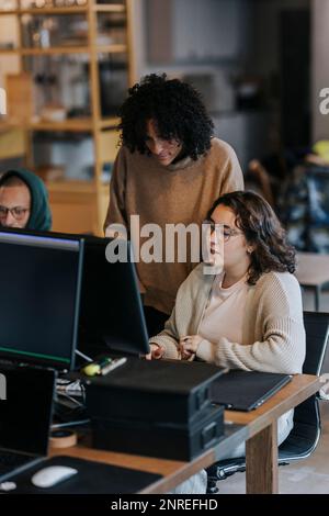 Multiracial business colleagues discussing over computer at desk in office Stock Photo