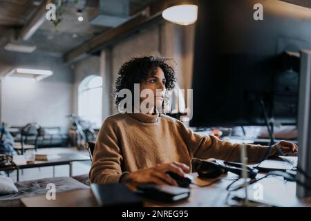 Female programmer concentrating while working on computer at desk in office Stock Photo