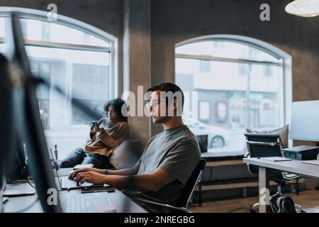 Male computer programmer using laptop while working in startup company Stock Photo