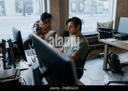 Young businessman working on laptop at desk in creative office Stock Photo