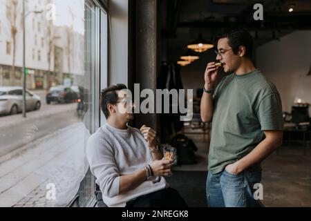 Young male entrepreneurs having cookies during break time at creative workplace Stock Photo