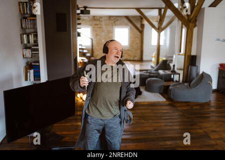 Carefree senior man dancing while listening to music at home Stock Photo