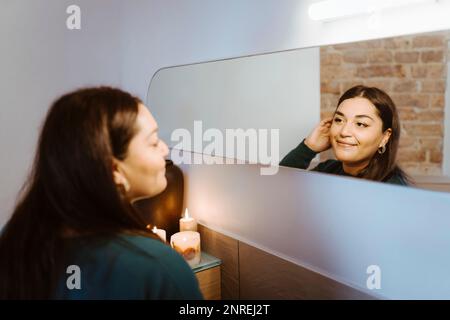 Smiling woman looking at refection in mirror at home Stock Photo