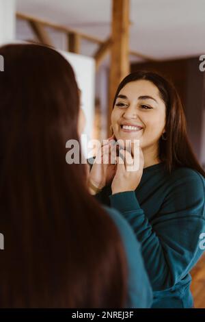 Woman looking in mirror and smiling at home Stock Photo