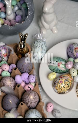 photo in a bird's nest for quail eggs, next to a rabbit and decorative chicken eggs on the table Stock Photo