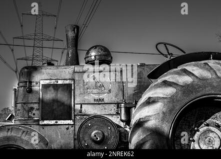 A vintage Field Marshall tractor parked under an electricity pylon and transmission line at a vintage vehicle rally in Wisborough Green, UK. Stock Photo