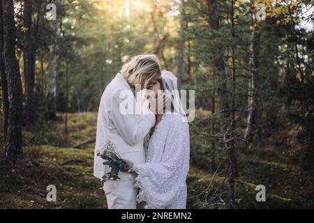 Newly married couple kissing in forest on wedding day Stock Photo