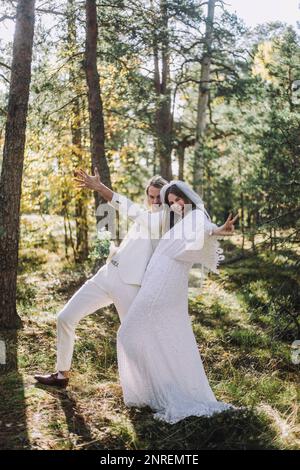 Cheerful newlywed bride and groom gesturing in forest Stock Photo